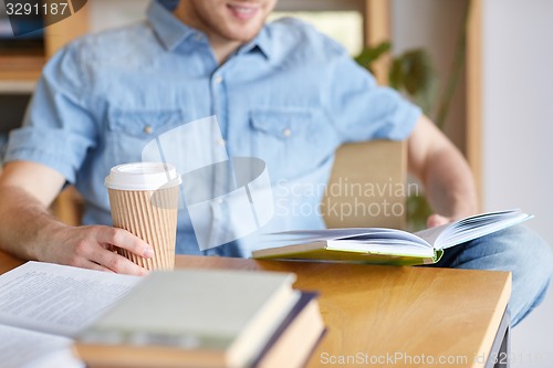 Image of happy student reading book and drinking coffee