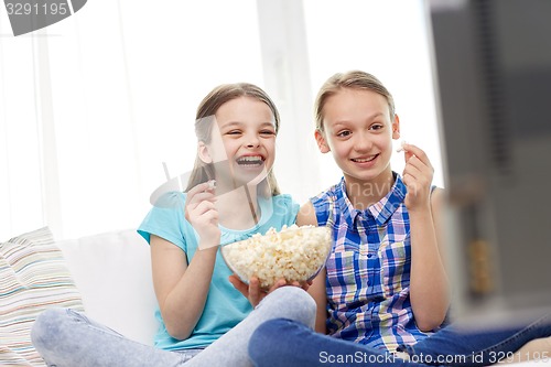 Image of happy girls with popcorn watching tv at home