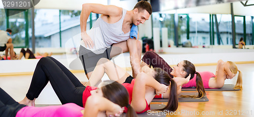 Image of group of smiling women doing sit ups in the gym