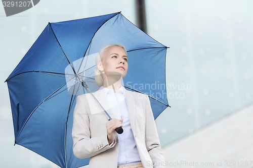 Image of young serious businesswoman with umbrella outdoors