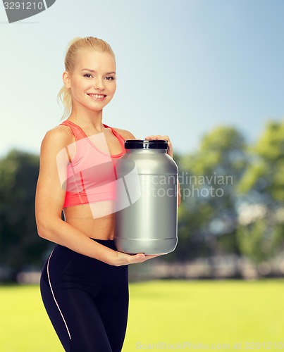 Image of smiling sporty woman with jar of protein