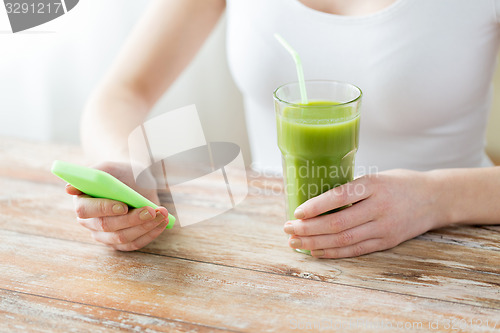 Image of close up of woman with smartphone and green juice