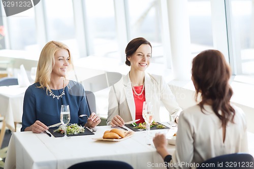 Image of happy women eating and talking at restaurant
