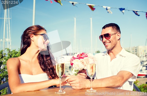 Image of smiling couple with bunch and champagne at cafe