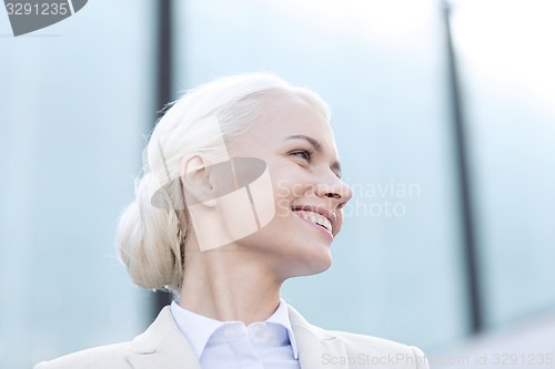 Image of young smiling businesswoman over office building