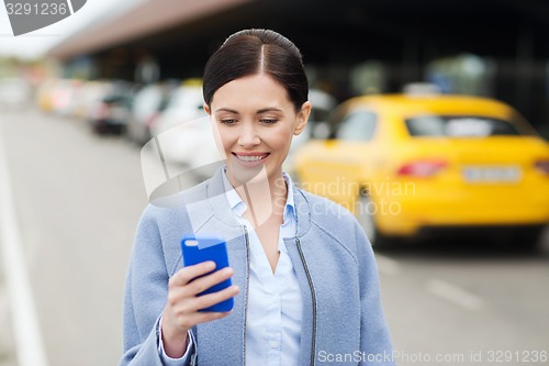 Image of smiling woman with smartphone over taxi in city
