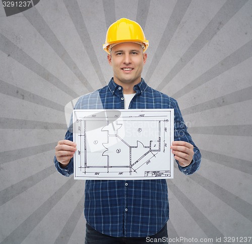 Image of smiling male builder in helmet with blueprint