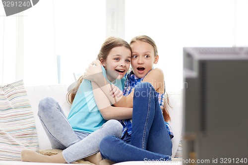 Image of scared little girls watching horror on tv at home