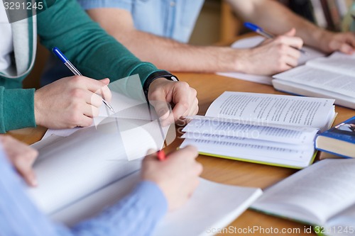 Image of close up of hands with books writing to notebooks