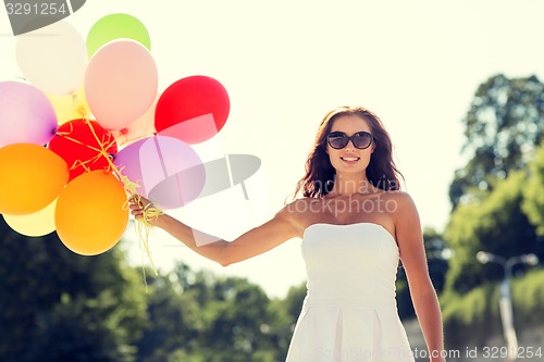 Image of smiling young woman in sunglasses with balloons