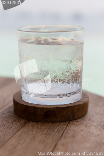 Image of glass of water with ice cubes on table at beach