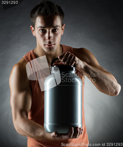 Image of young male bodybuilder holding jar with protein