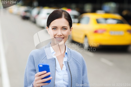 Image of smiling woman with smartphone over taxi in city