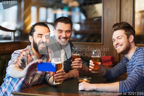 Image of male friends with smartphone drinking beer at bar