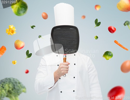 Image of male chef cook covering face with grill pan