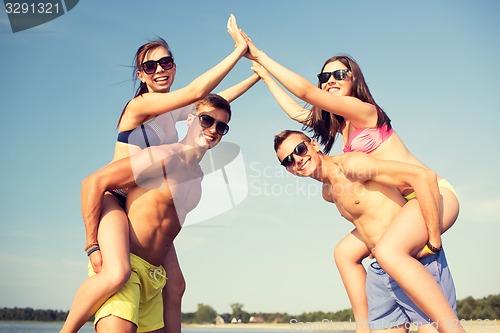 Image of smiling friends in sunglasses on summer beach