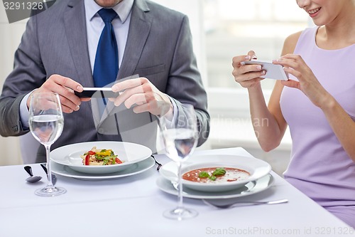 Image of close up of couple with smartphones at restaurant