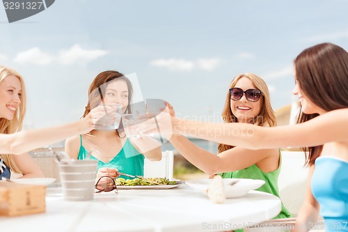 Image of smiling girls looking at tablet pc in cafe