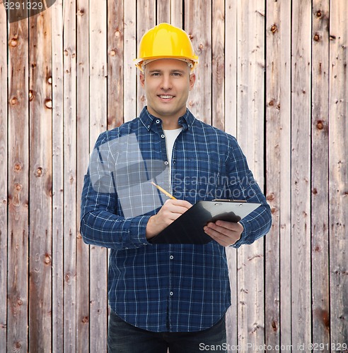 Image of smiling male builder in helmet with clipboard