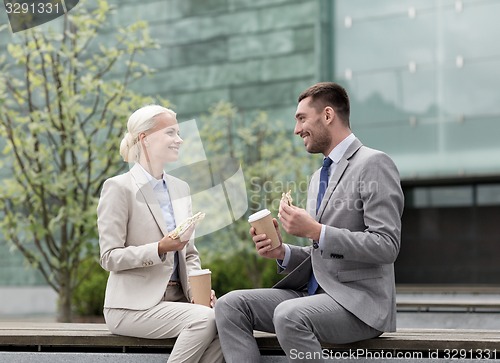 Image of smiling businessmen with paper cups outdoors