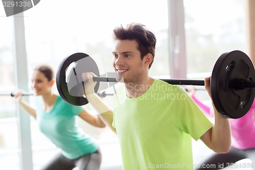 Image of group of people exercising with barbell in gym