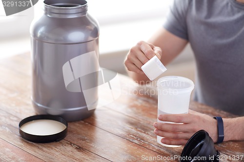 Image of close up of man with protein shake bottle and jar