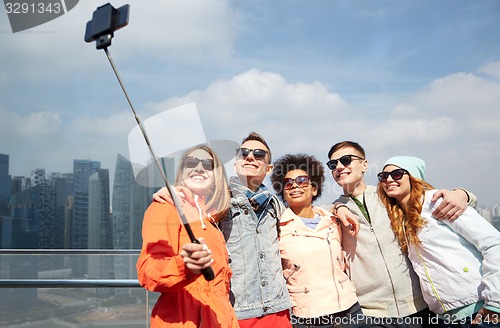 Image of smiling friends taking selfie with smartphone