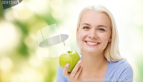 Image of happy woman eating green apple