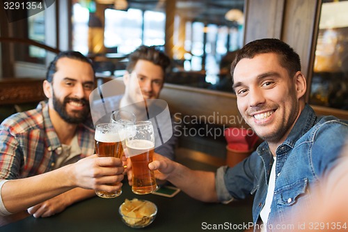 Image of friends taking selfie and drinking beer at bar