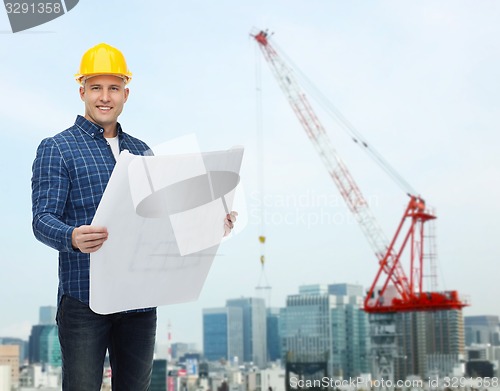 Image of smiling male builder in helmet with blueprint