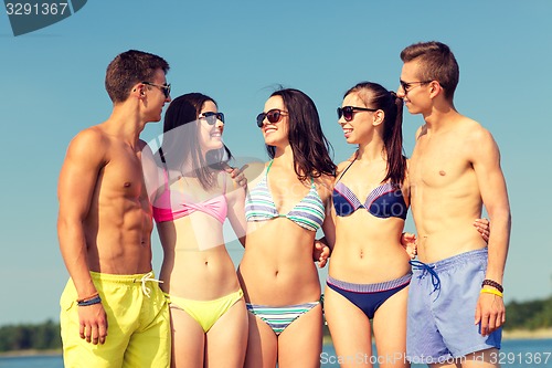 Image of smiling friends in sunglasses on summer beach