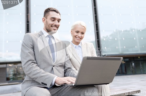 Image of smiling businesspeople with laptop outdoors