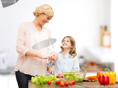 Image of happy family cooking vegetable salad for dinner