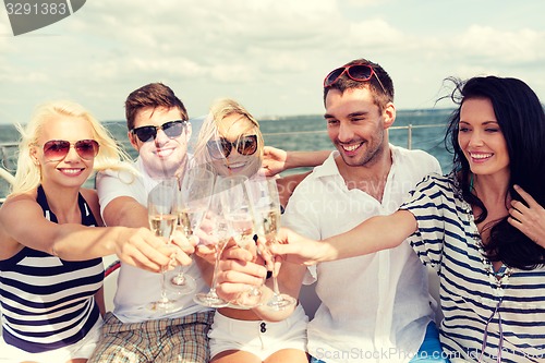 Image of smiling friends with glasses of champagne on yacht