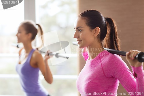 Image of group of people exercising with bars in gym