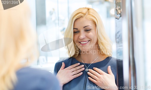 Image of happy woman choosing pendant at jewelry store