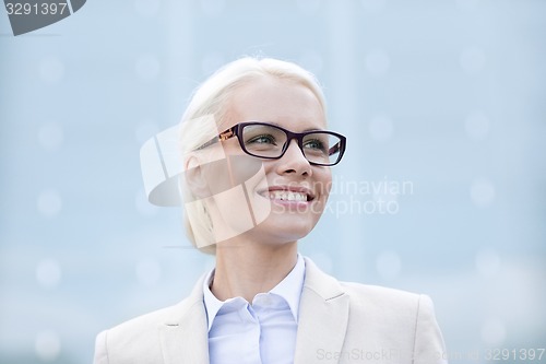 Image of young smiling businesswoman over office building