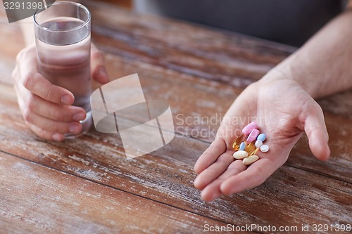 Image of close up of male hands holding pills and water