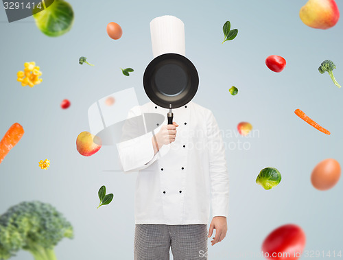 Image of male chef cook covering face with frying pan