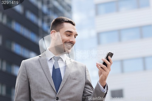Image of smiling businessman with smartphone outdoors