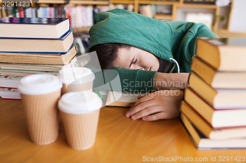 Image of tired student or man with books in library