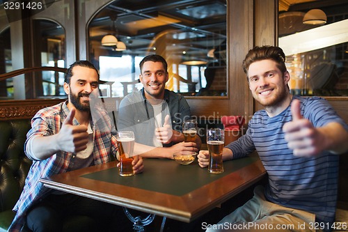 Image of happy male friends drinking beer at bar or pub