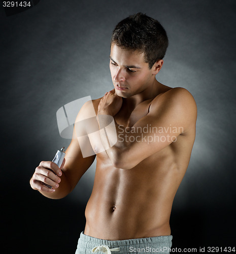 Image of young male bodybuilder applying pain relief gel