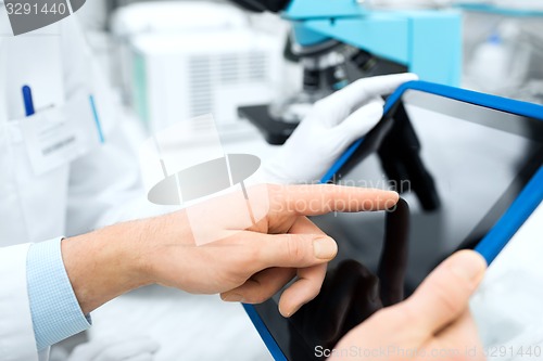 Image of close up of scientists hands with tablet pc in lab