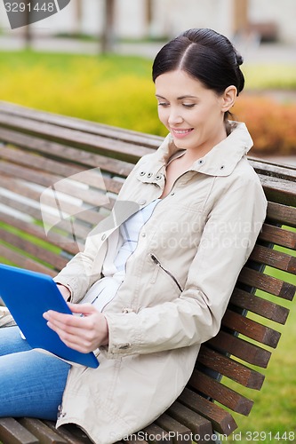 Image of woman with tablet pc sitting on bench in park