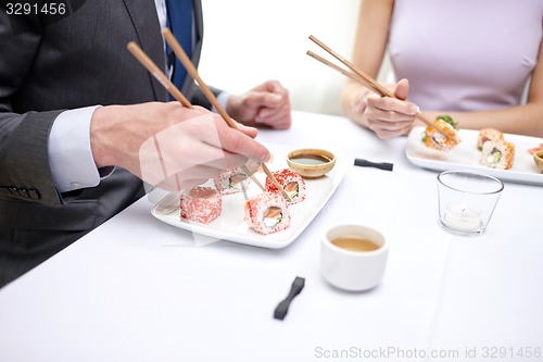 Image of close up of couple eating sushi at restaurant