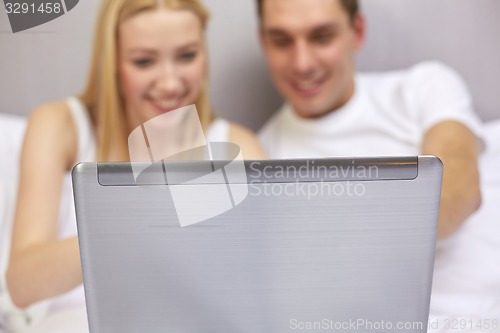 Image of smiling couple in bed with laptop computer