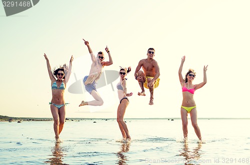 Image of smiling friends in sunglasses on summer beach