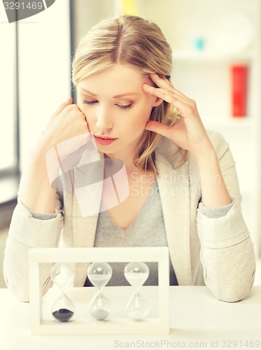 Image of pensive businesswoman with sand glass