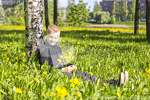 Image of Ten year boy sits under birch